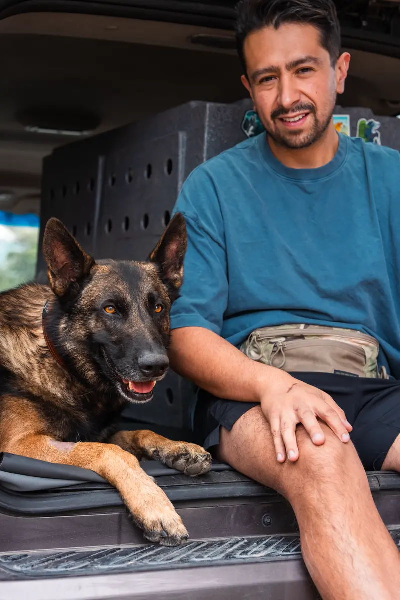 Henry of GTX K9 Dog Training sitting beside a dog at a vehicle